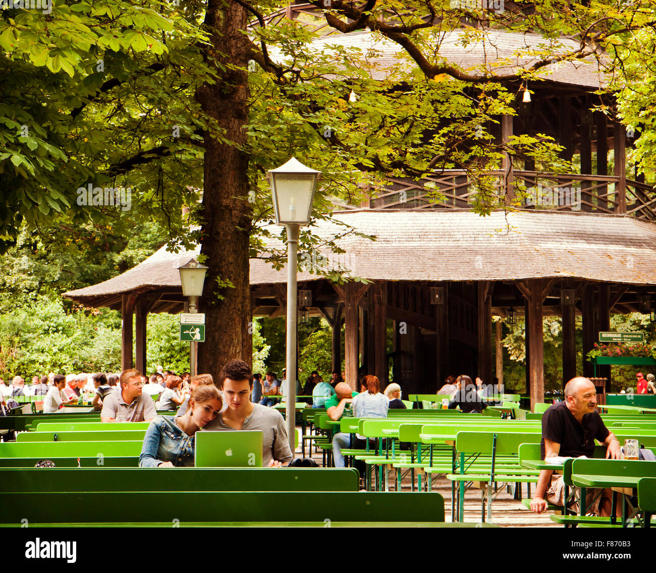 Munich, Germany - couple working at laptop outdoors sitting at Chinese tower beer garden of Englisher Garten. Stock Photo