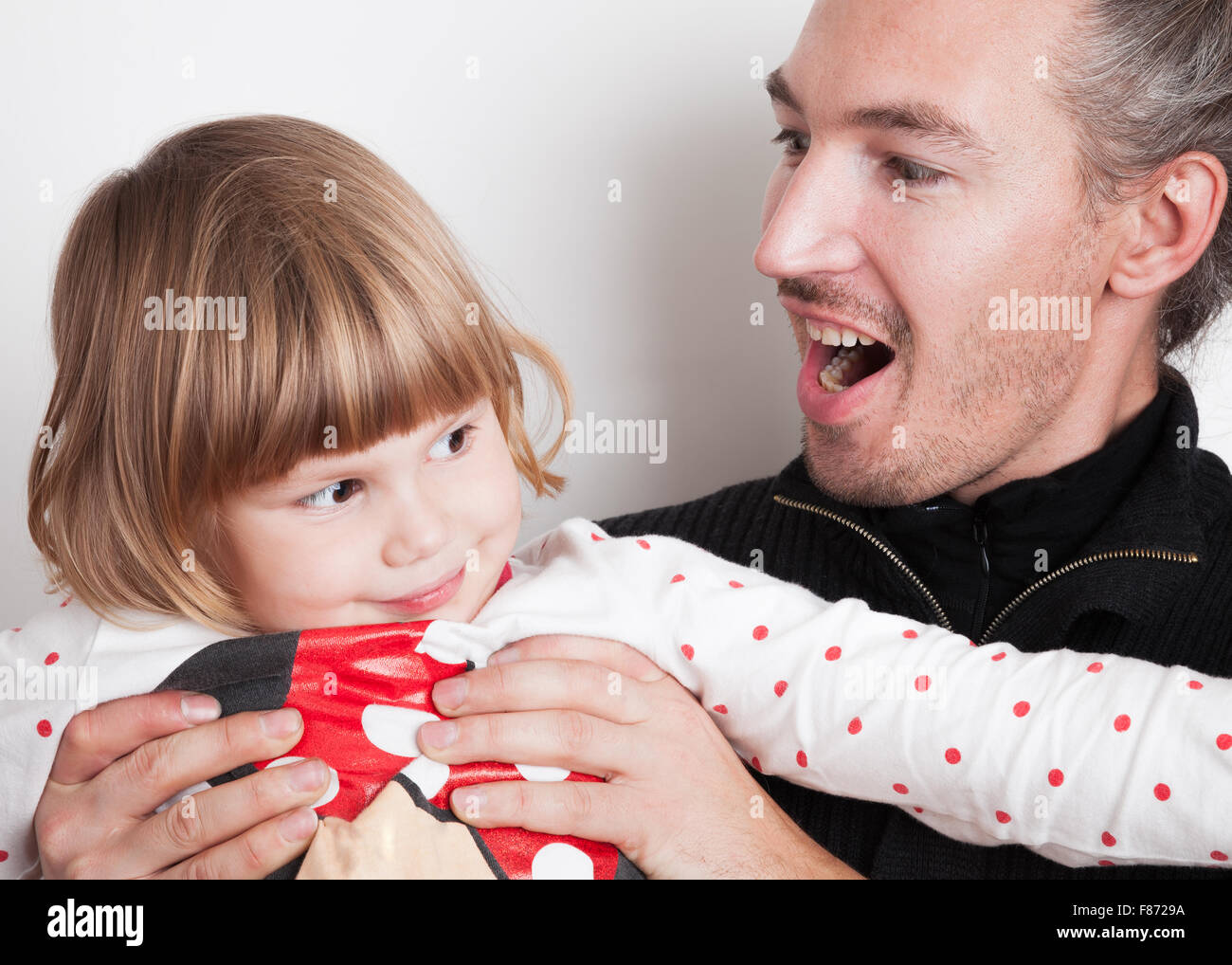 Positive young man with little blond Caucasian girl, studio portrait over white wall background Stock Photo