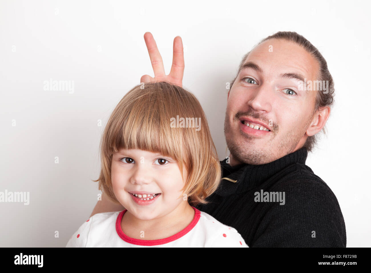 Young man with little blond Caucasian girl, studio portrait over white wall background Stock Photo