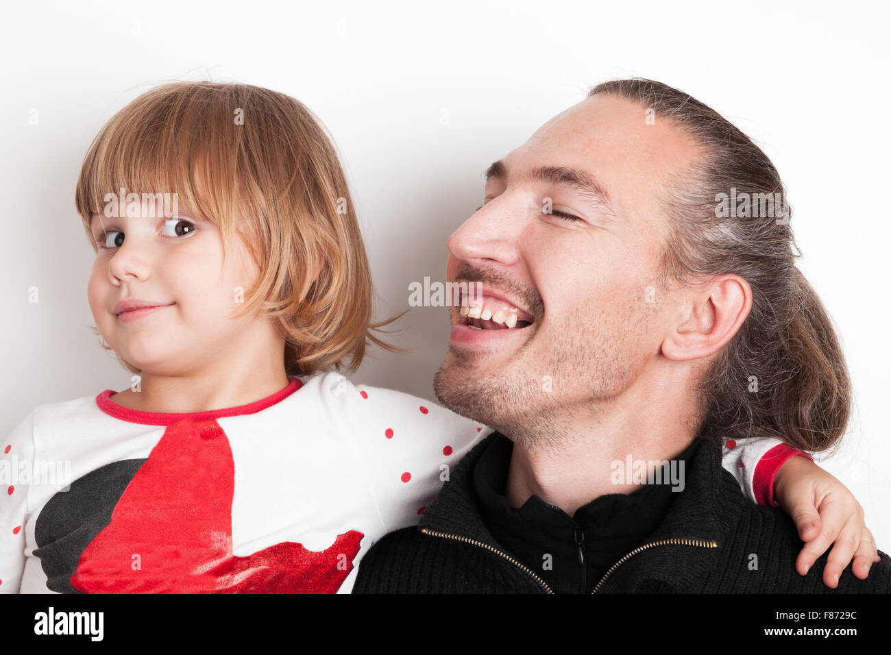 Smiling Young man with little blond Caucasian girl, studio portrait over white wall background Stock Photo