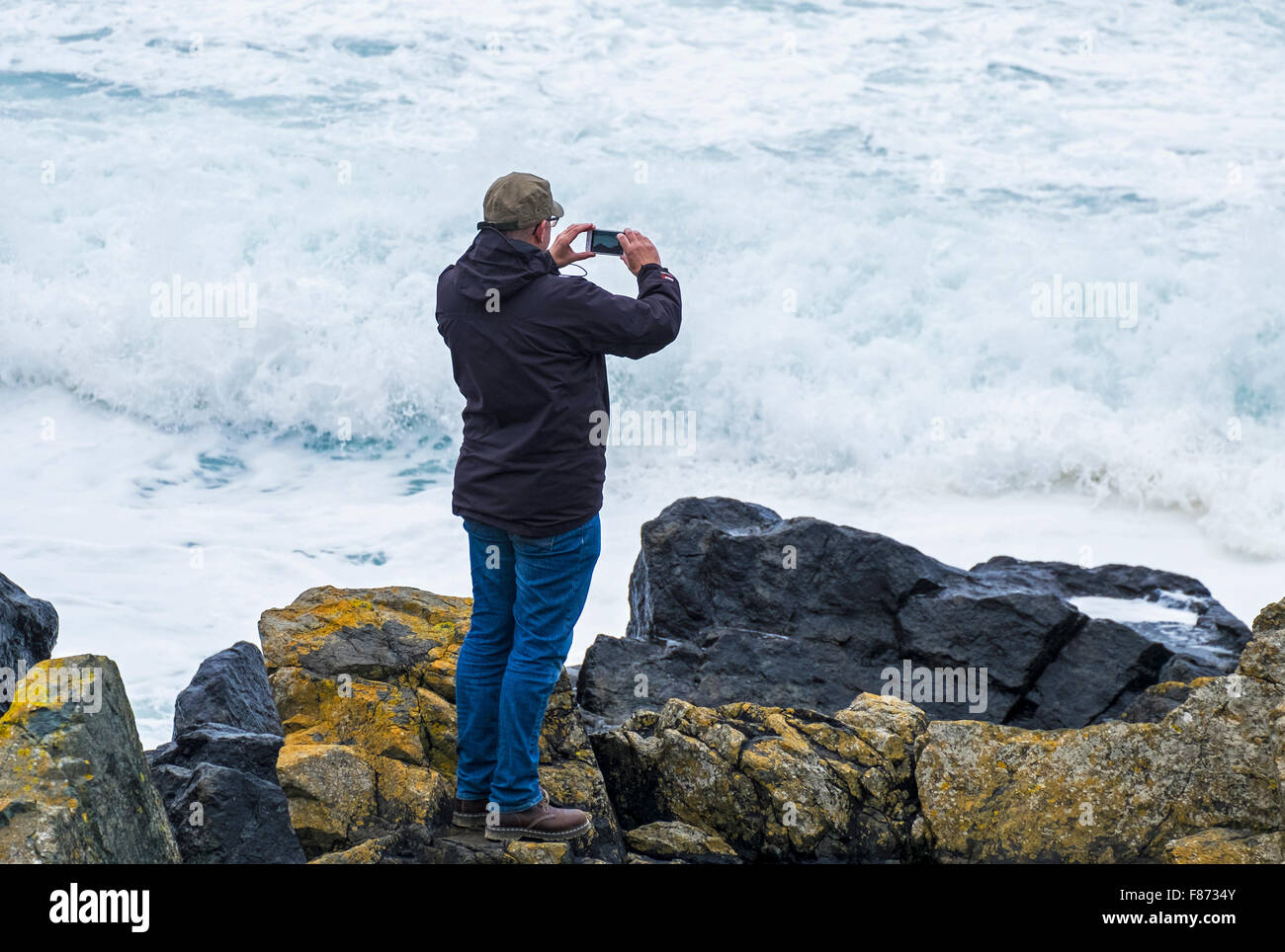man taking photograph of waves at the coast Stock Photo