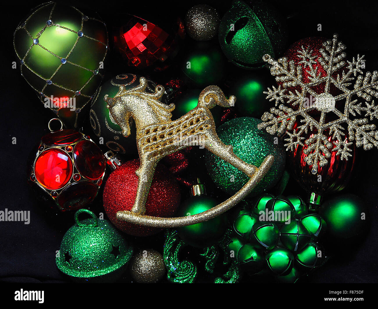 A collection of Christmas decorations featuring a gold rockinghorse bauble, green baubles, gold snowflake. Stock Photo