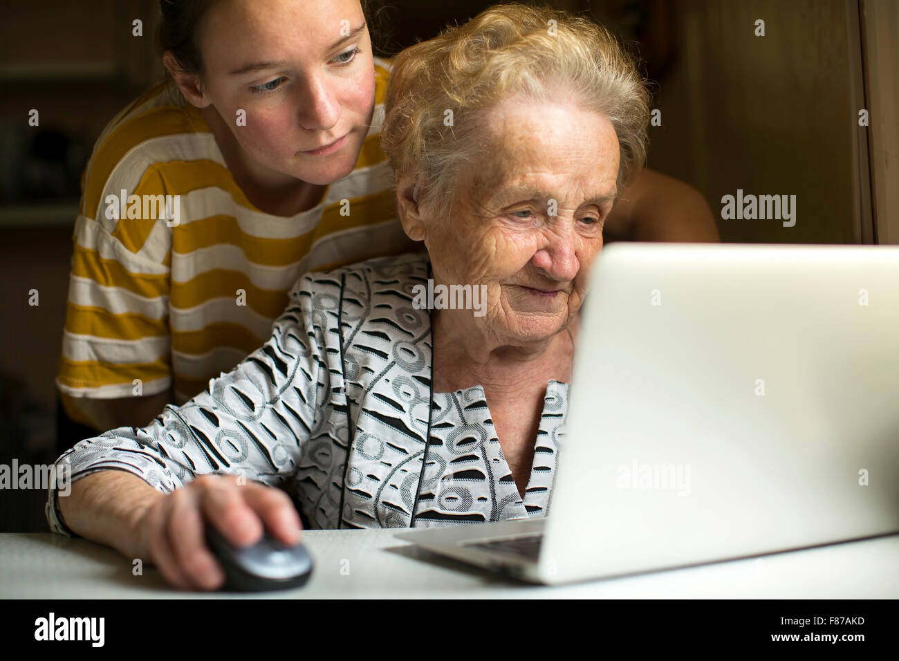 Mature woman learns from the granddaughter to work on the computer. Stock Photo