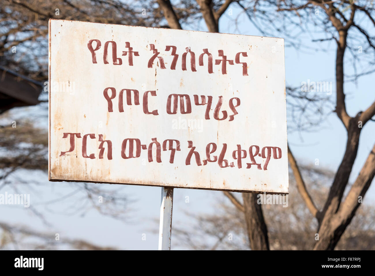 An Amharic sign in Awash, Ethiopia stating no weapons or pets are allowed in the (national) park. Stock Photo