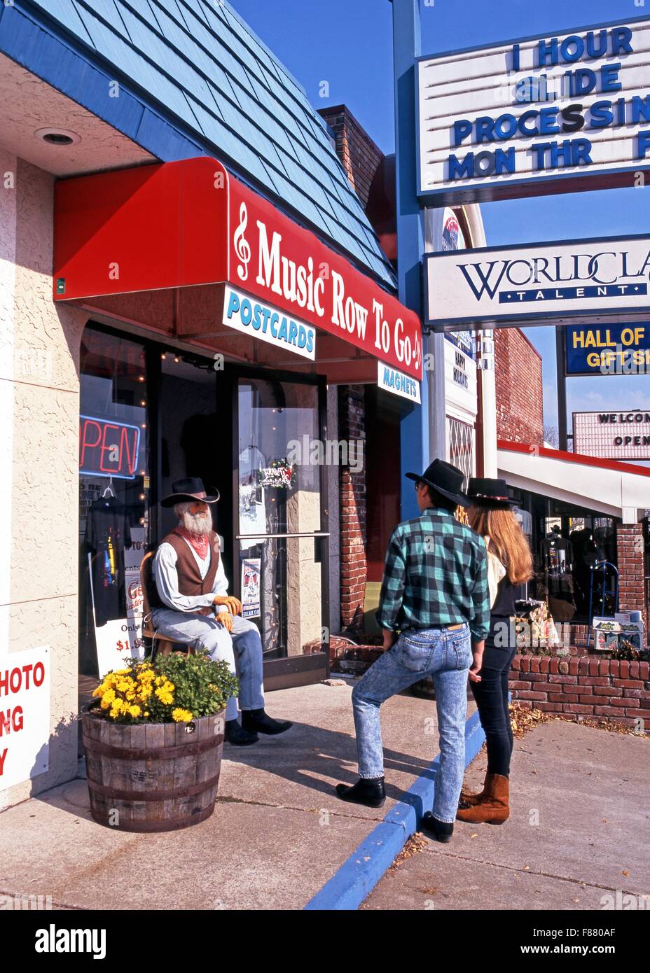 Cowboy couple looking at a statue of an old man cowboy sitting on a