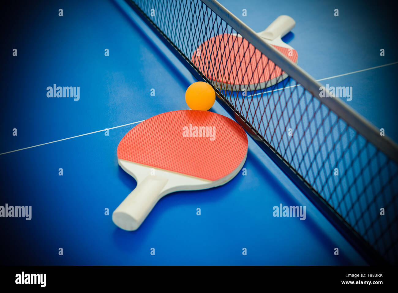 pingpong rackets and ball highlighted on a blue pingpong table Stock Photo