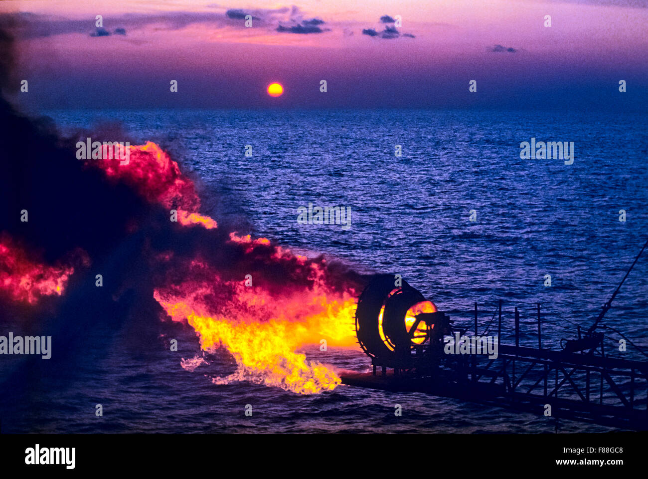 Gas burning flare on offshore oil rig at sunset, Indonesia, South East Asia Stock Photo