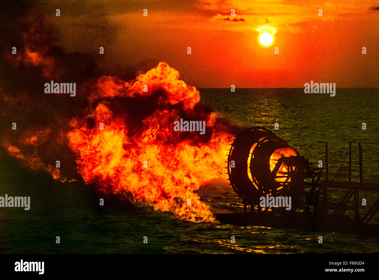 Gas burning flare on offshore oil rig at sunset, Indonesia South East Asia Stock Photo