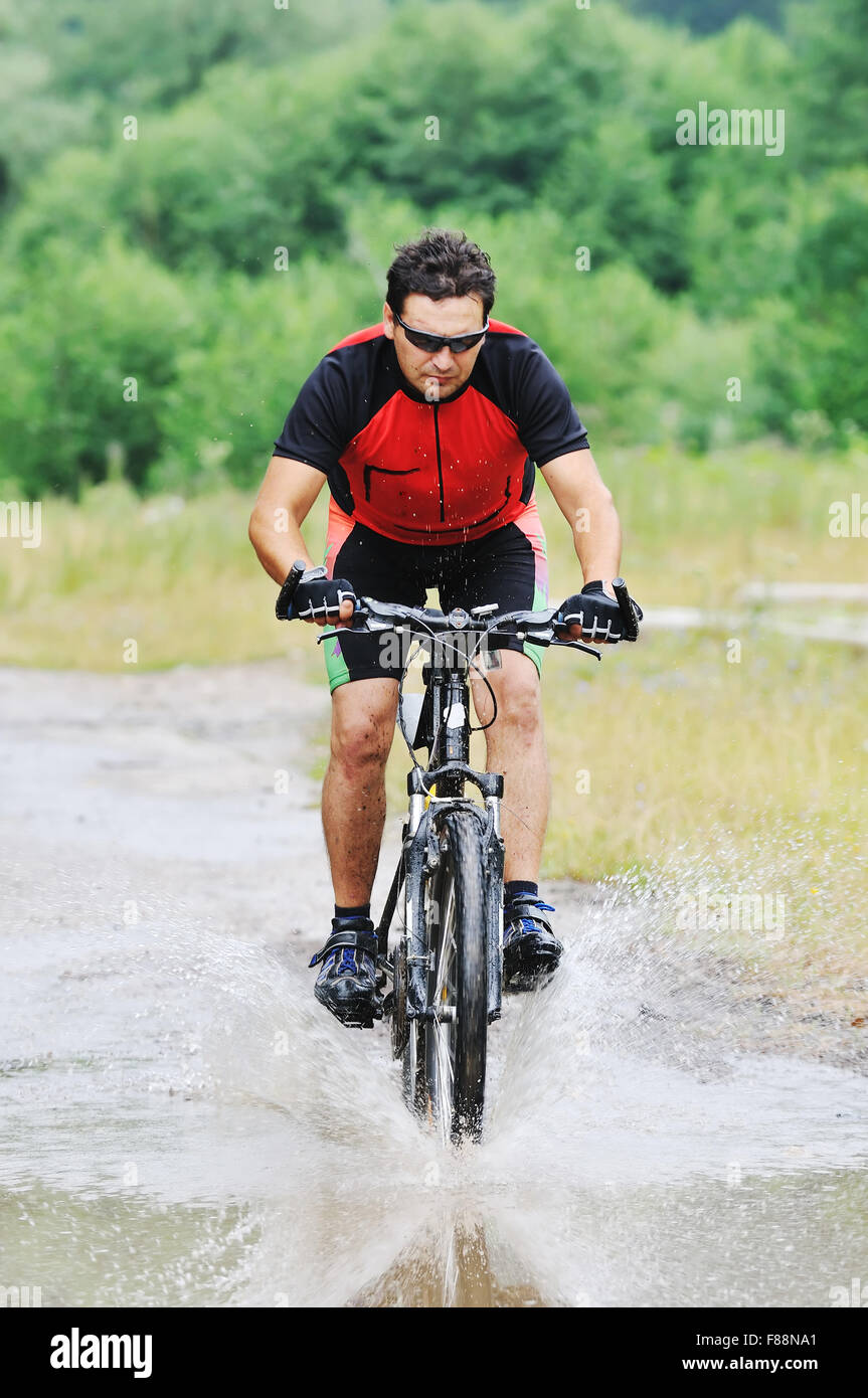 young man drive mountain bike over water river Stock Photo Alamy