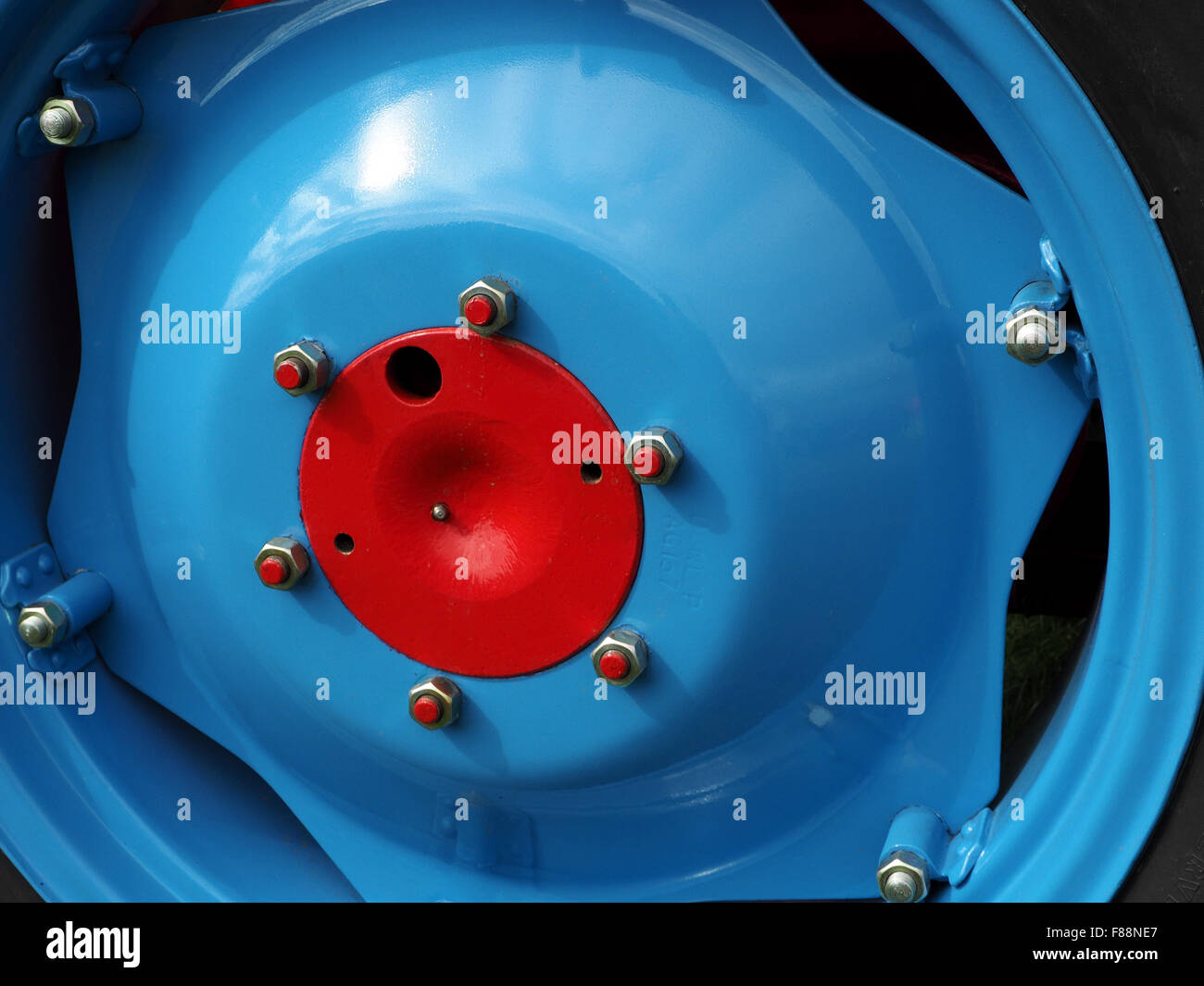 detail of blue classic tractor wheel with silver wheelnuts and red