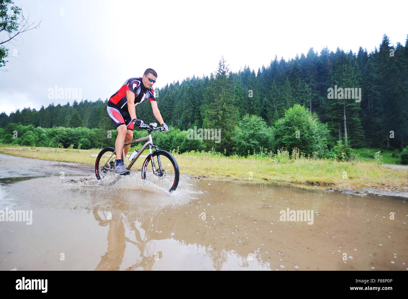 young man drive mountain bike over water river Stock Photo Alamy