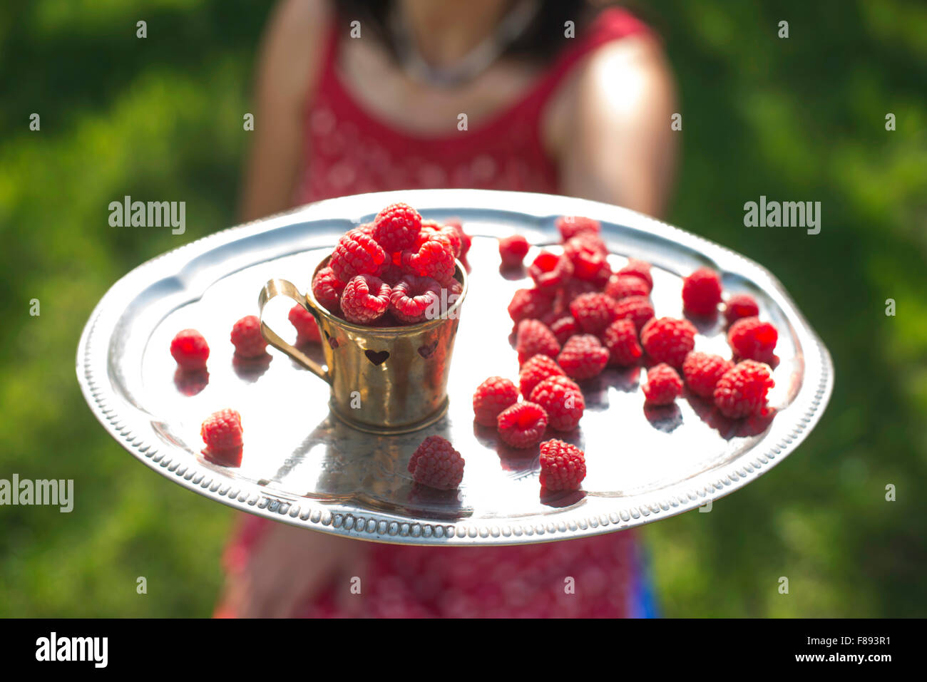 Woman in red dress holding a cup of raspberries Stock Photo - Alamy