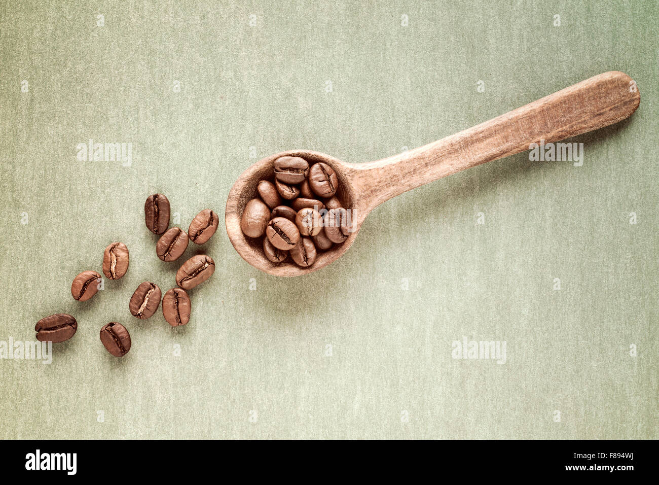 Spoon with coffee crop beans on paper background Stock Photo