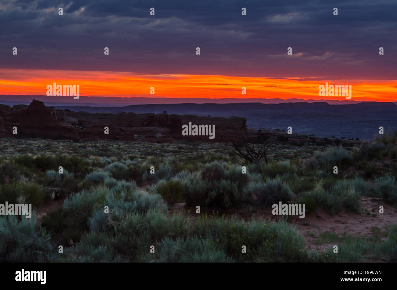 The sky turns brilliant pink and orange as dawn breaks over a vast desert in Utah Stock Photo