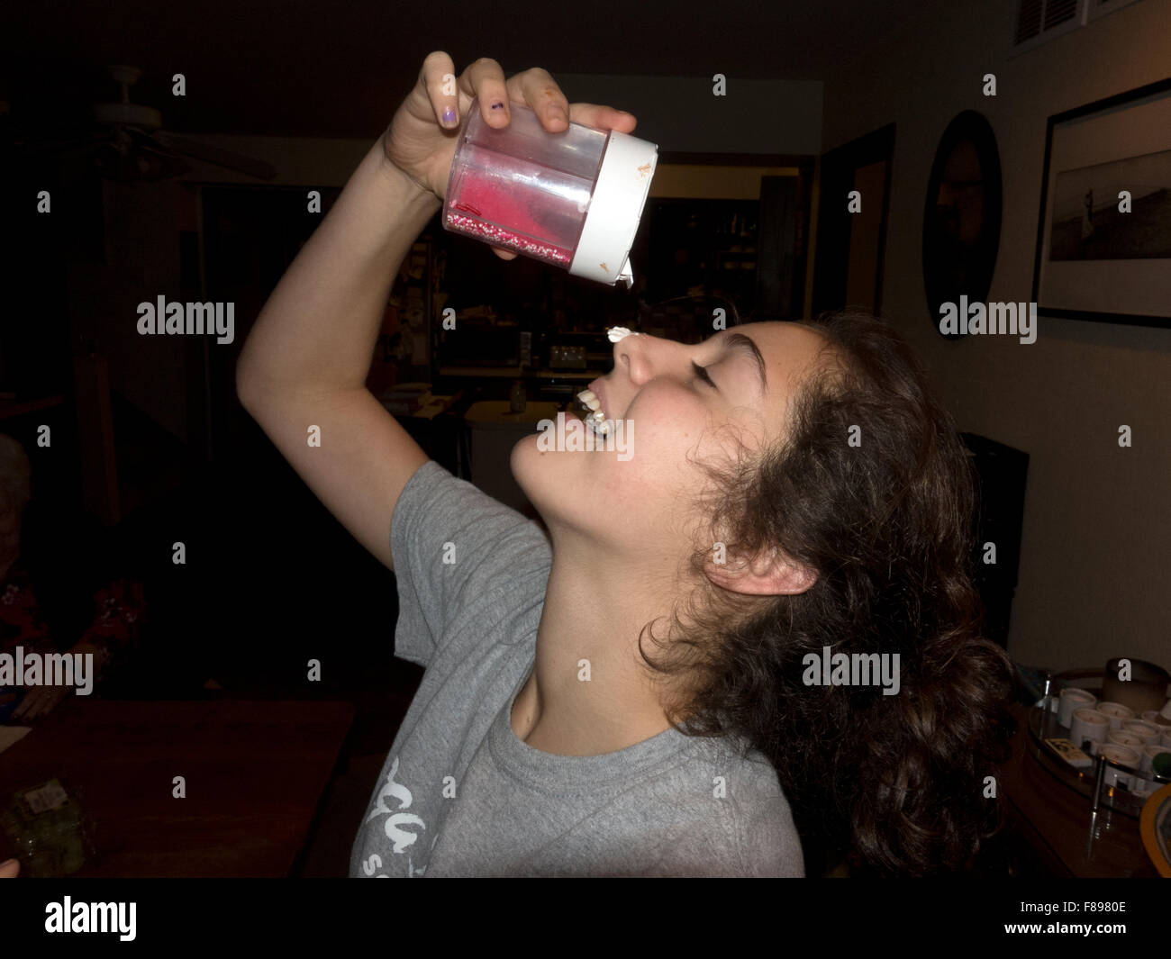 Teenage girl age 15 applying sprinkles to whip cream on her nose. Downers Grove Illinois IL USA Stock Photo