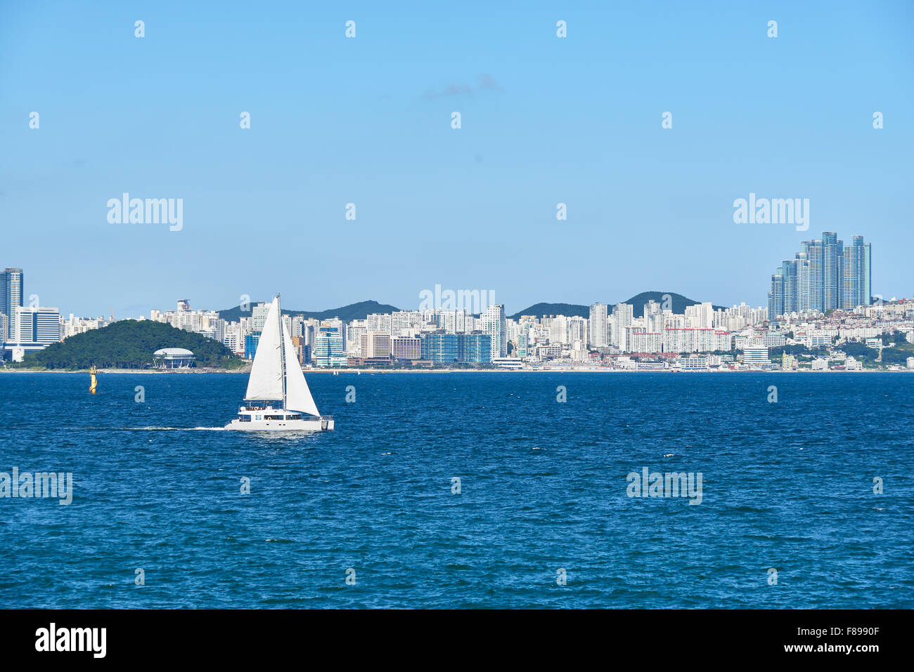 white luxury yacht sailing at sea on a background of Haeundae in Busan, Korea. Stock Photo