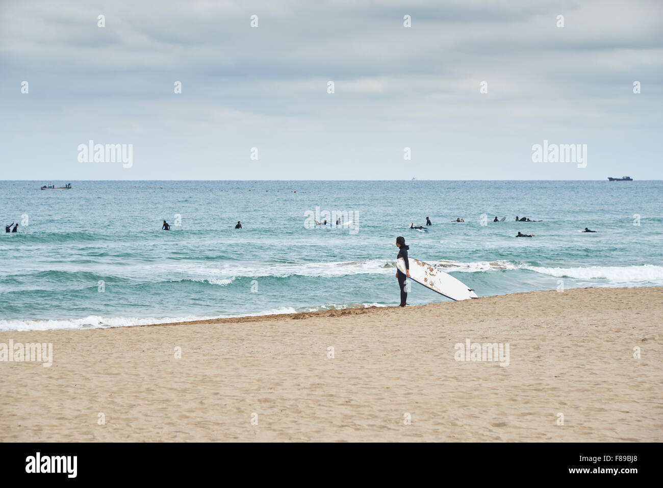 Landscape of Songjeong Beach with a woman holding surfing bard. The beach is located near the Haeundae beach in Busan and it has Stock Photo