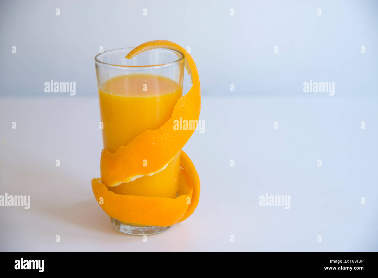 Glass of orange juice with the peel coiled around the glass. Stock Photo