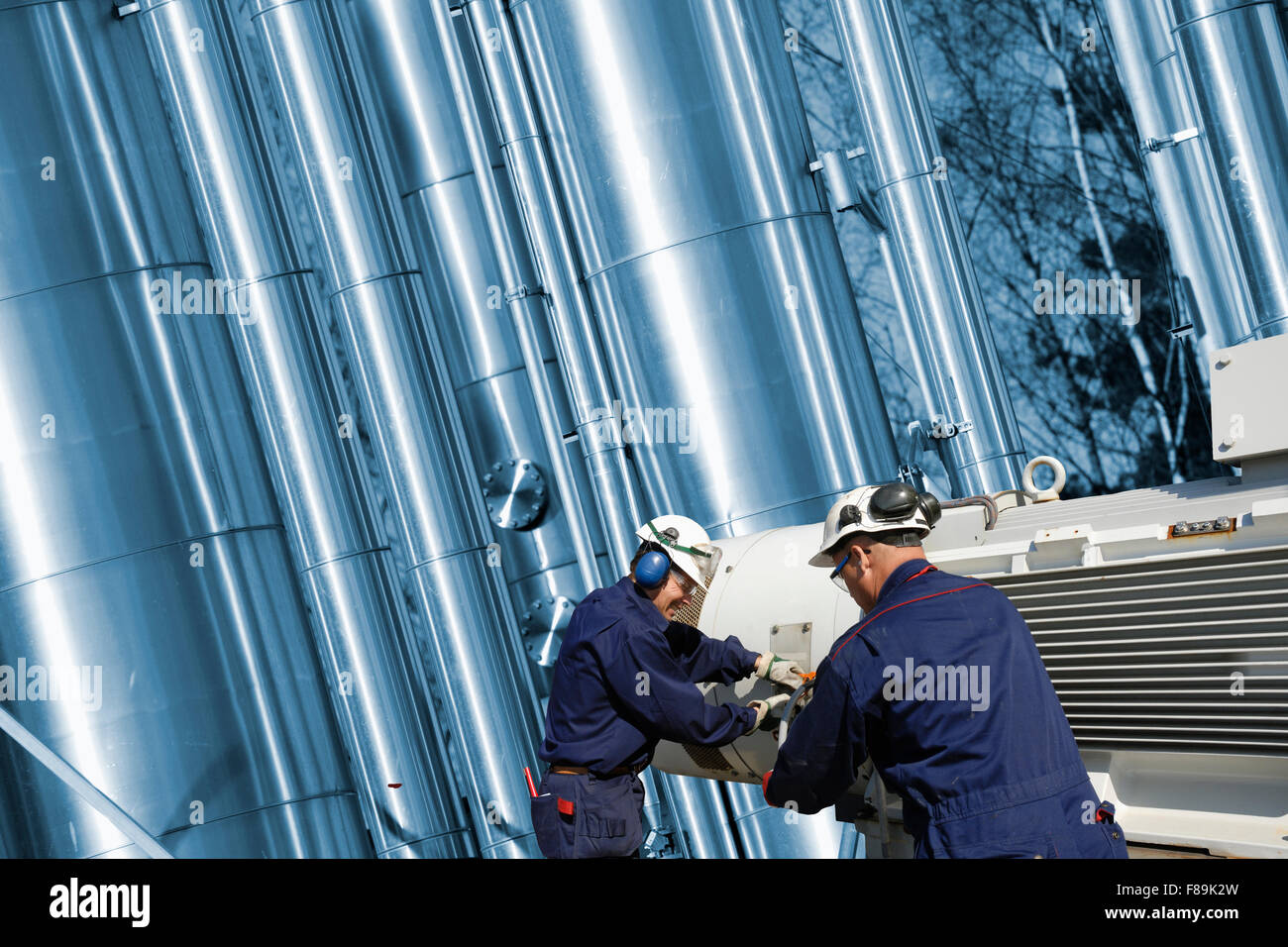 oil and gas workers in front of giant pipelines Stock Photo