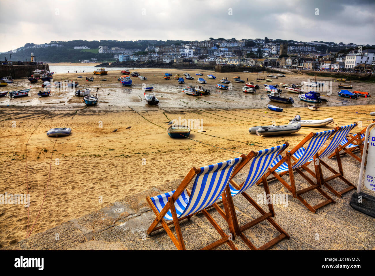 St Ives bay beach Cornwall UK England deck chairs looking to harbour harbor coast coastline fishing boats waiting for tide sand Stock Photo