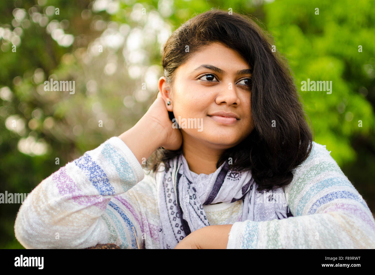 Portrait of a cute chubby round face Indian teenage girl looking up and thi...