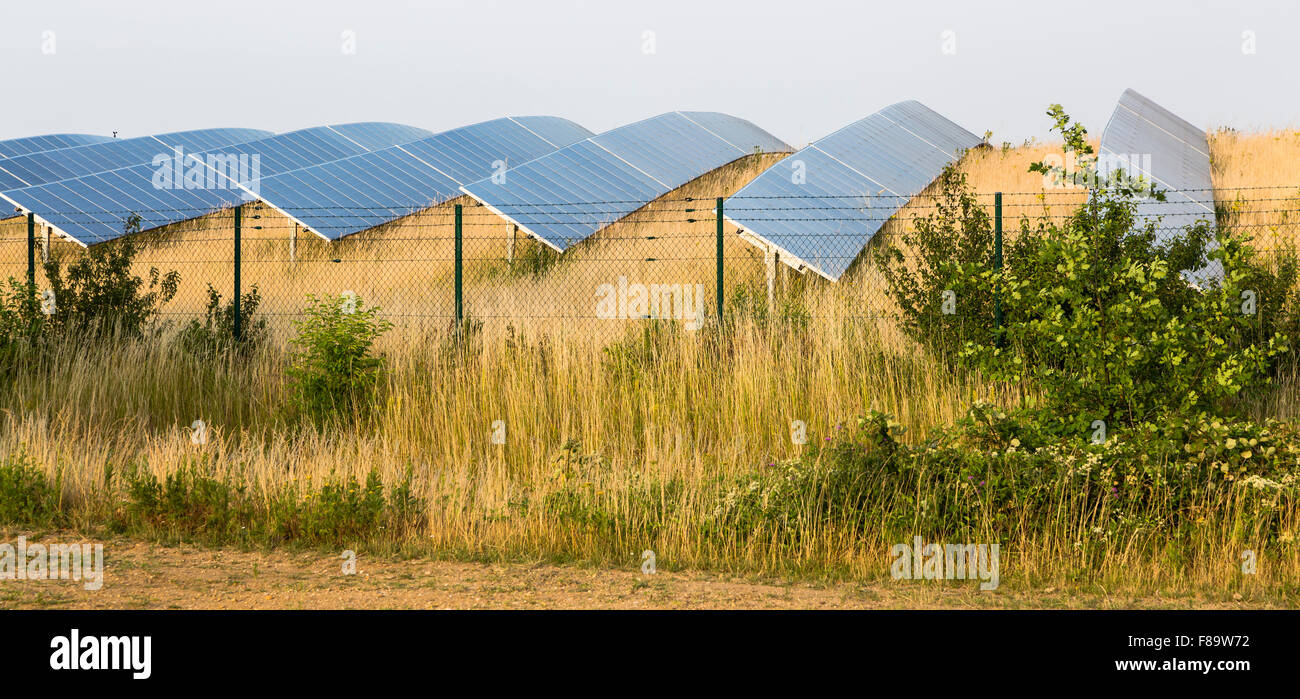 View to a large solar panel park behind a fence in green landscape. Stock Photo