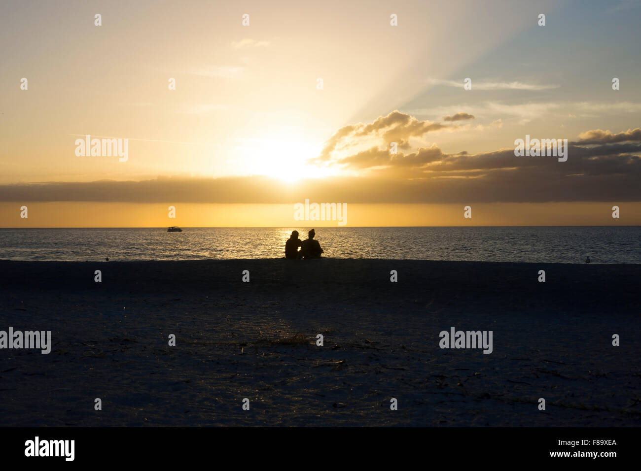 A Couple enjoys an Astonishing Golden Sunset at Sand Key Beach, Gulf of Mexico, Clearwater, Florida, USA Stock Photo