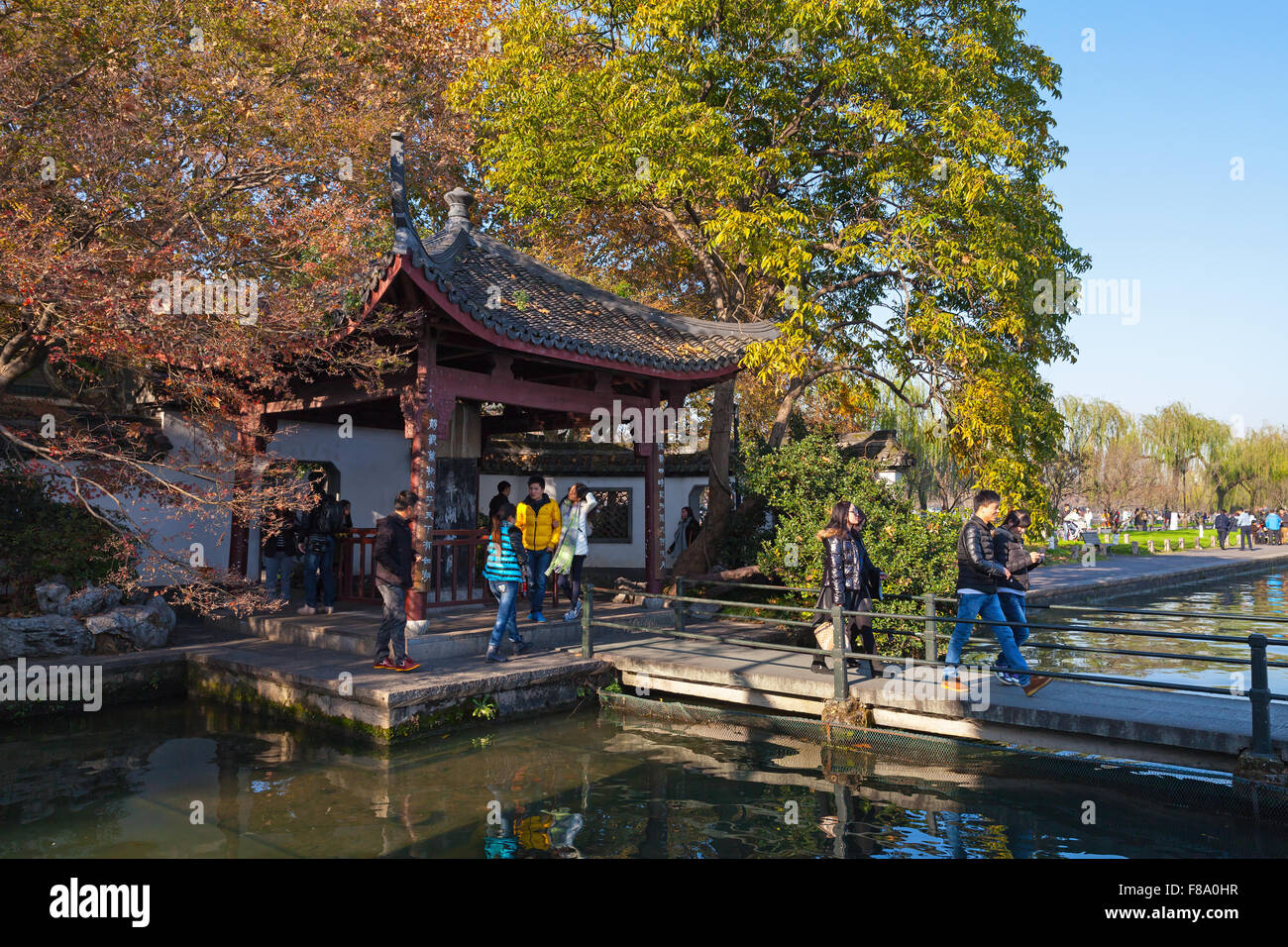 Hangzhou, China - December 5, 2014: traditional Chinese wooden gazebo on the West Lake coast. Ordinary people walking Stock Photo