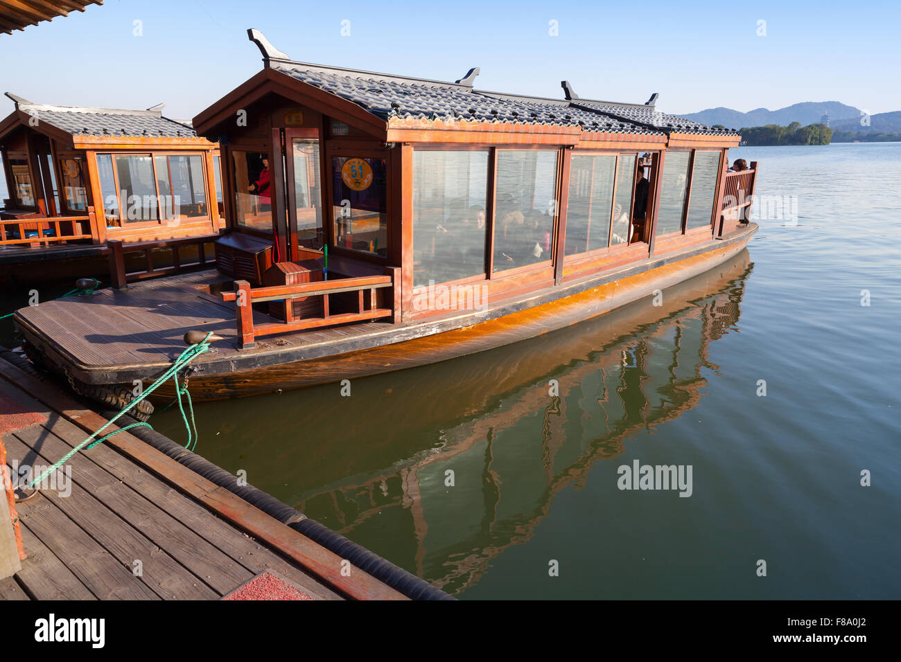 Hangzhou, China - December 5, 2014: Traditional Chinese wooden boat with passengers on the West Lake, famous park in Hangzhou Stock Photo