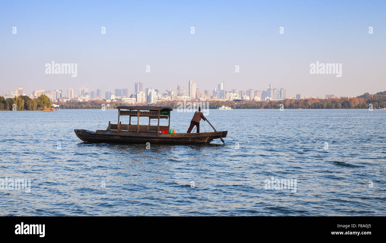 Hangzhou, China - December 5, 2014: Traditional Chinese wooden recreation boat with boatman on the West Lake. Famous park Stock Photo