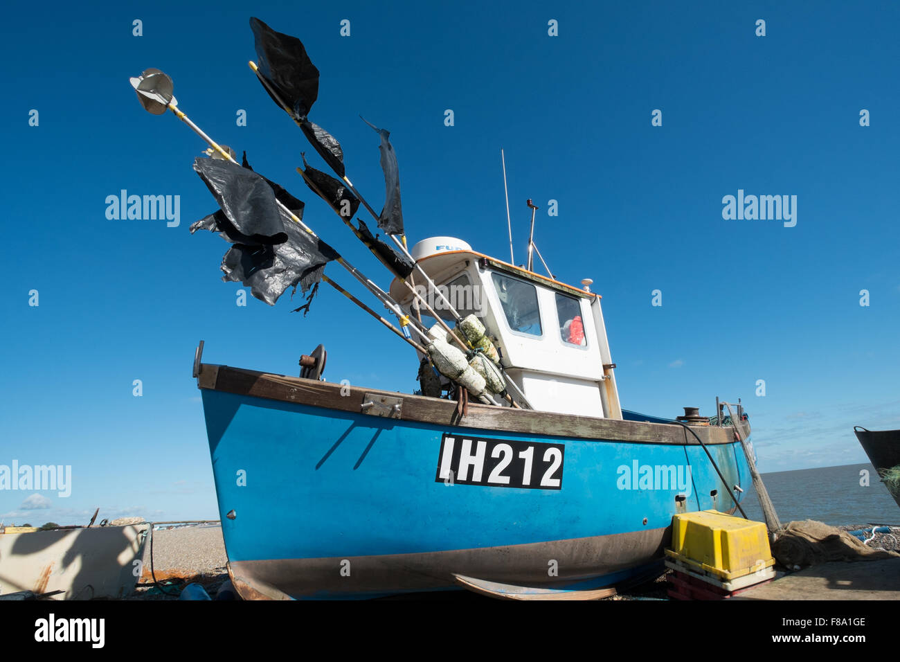 Blue hulled fishing boat with black flagged marker buoys on the beach at Aldeburgh Suffolk England Stock Photo