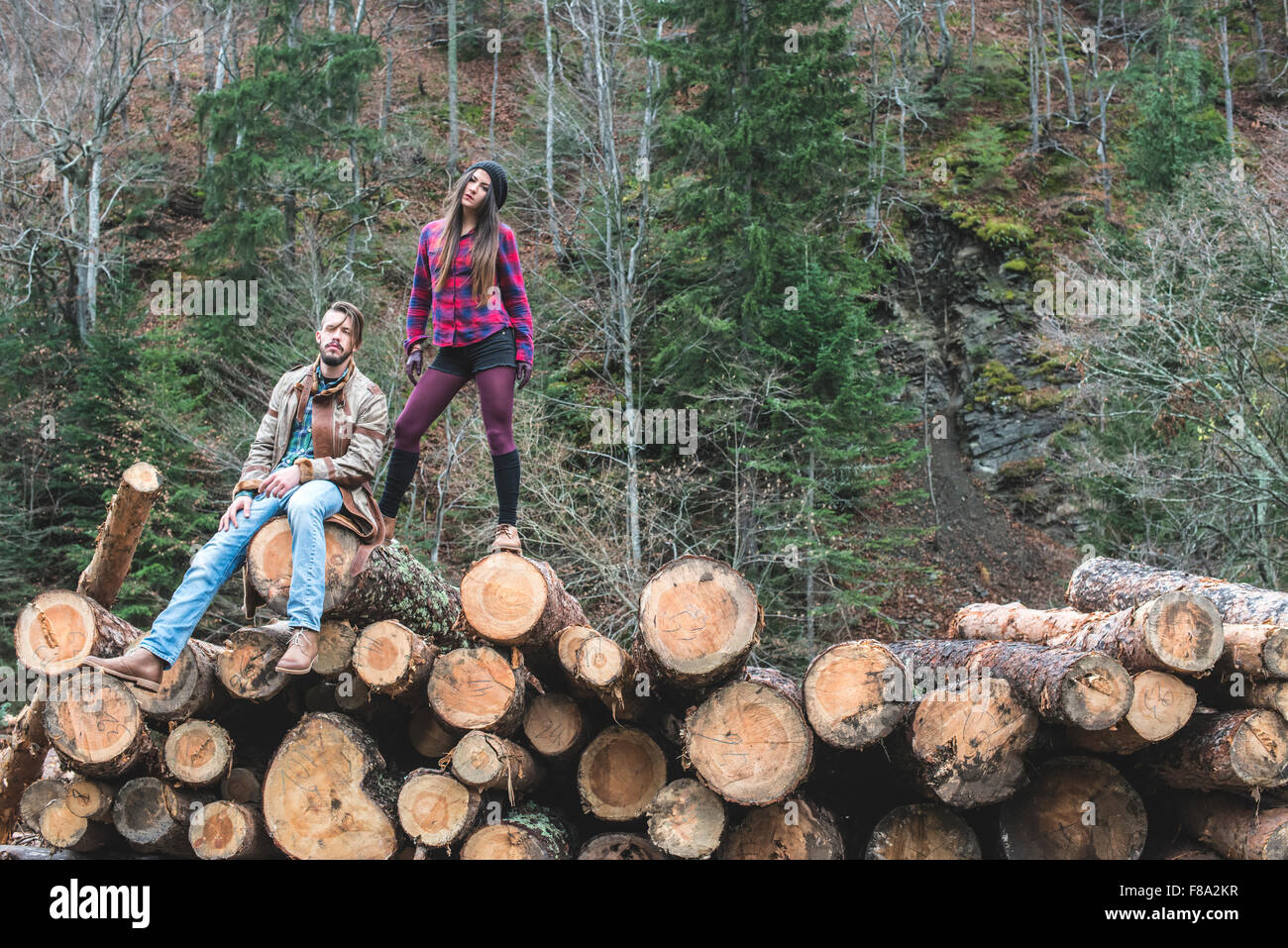 Young woman and men on wood logs in the forest Stock Photo - Alamy