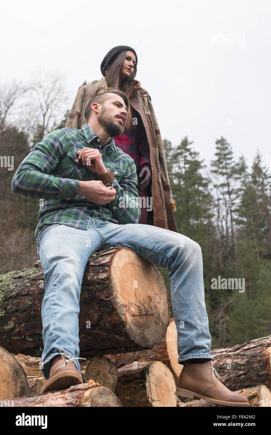 Young woman and men on wood logs in the forest Stock Photo - Alamy