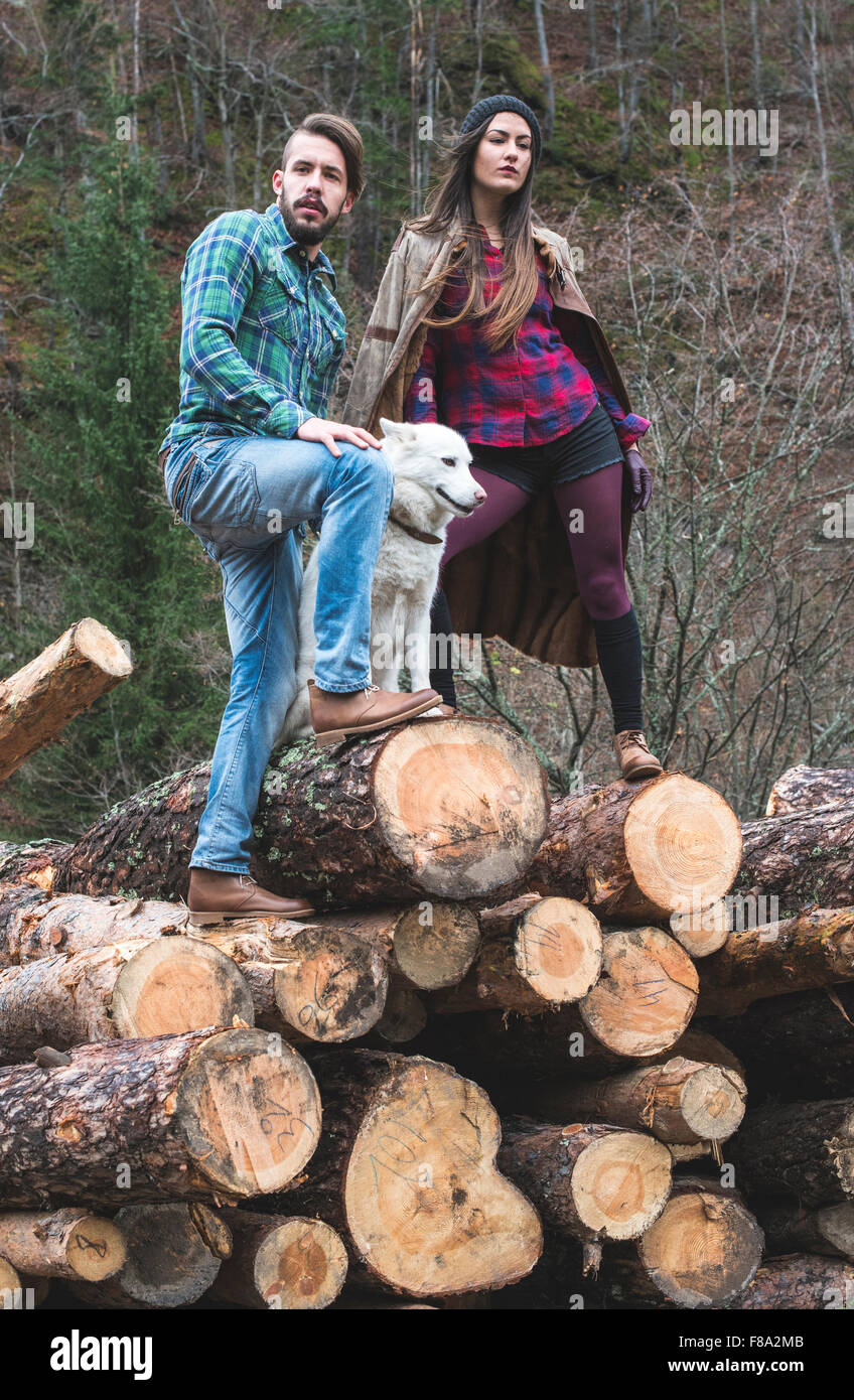 Young woman and men on wood logs in the forest. White dog Stock Photo ...