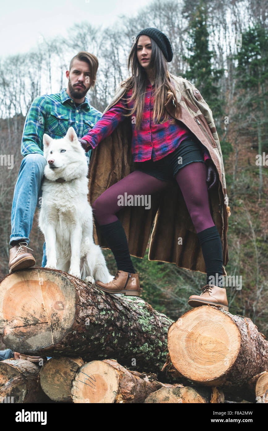 Young woman and men on wood logs in the forest. White dog Stock Photo ...