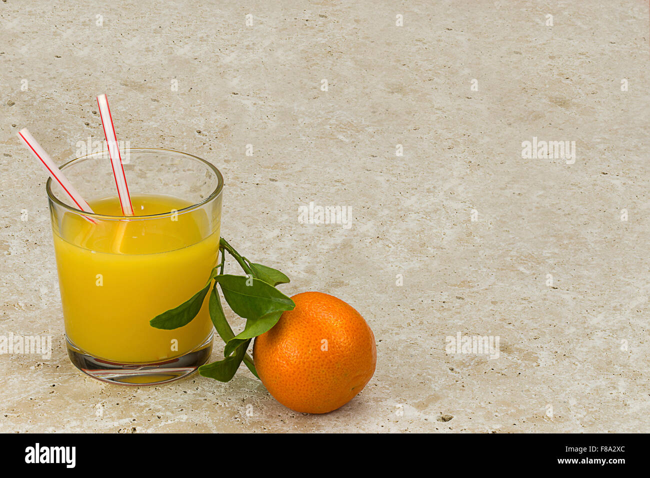 Satsuma orange on natural stone background with glass of orange juice