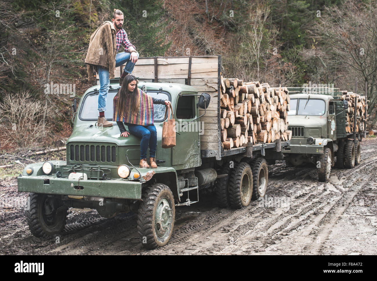 Young man and girl on truck with logs in the forest Stock Photo - Alamy