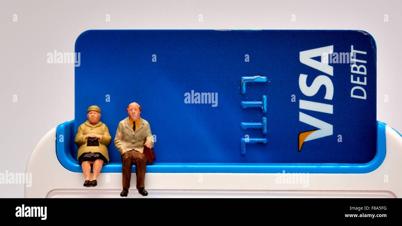 Two Miniature pensioner figures sitting on a pin sentry machine with a visa debit card inside