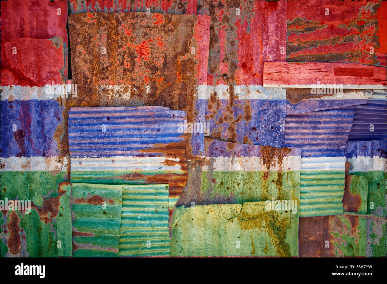An abstract background image of the flag of Gambia painted on to rusty corrugated iron sheets overlapping to form a wall Stock Photo
