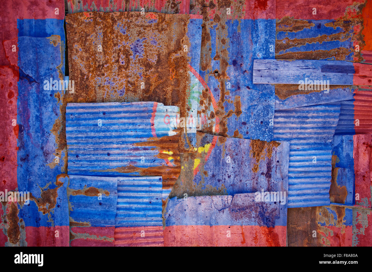 An abstract background image of the flag of Guam painted on to rusty corrugated iron sheets overlapping to form a wall or fence. Stock Photo
