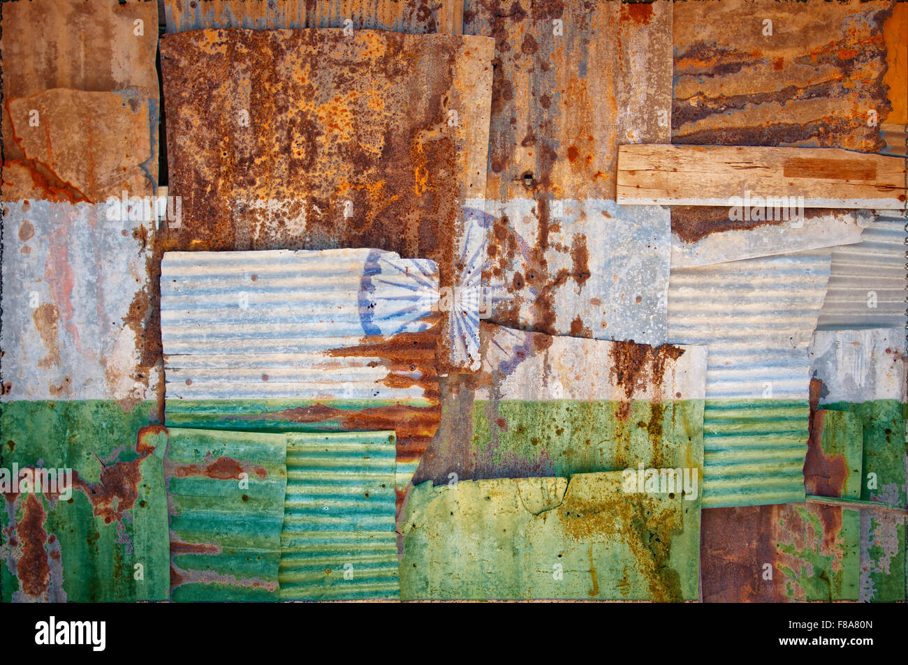 An abstract background image of the flag of India painted on to rusty corrugated iron sheets overlapping to form a wall or fence Stock Photo