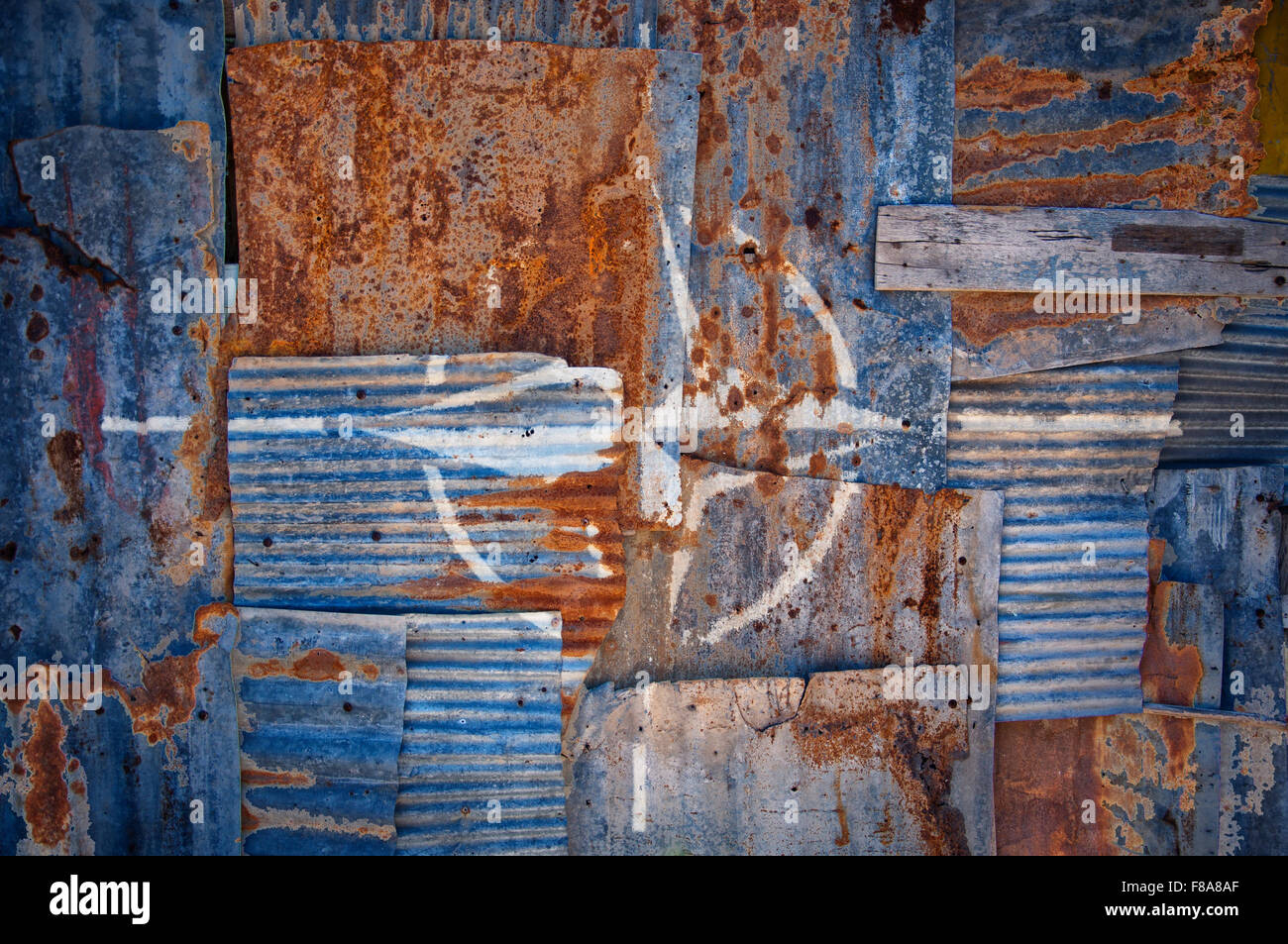 An abstract background image of the flag of NATO painted on to rusty corrugated iron sheets overlapping to form a wall or fence. Stock Photo