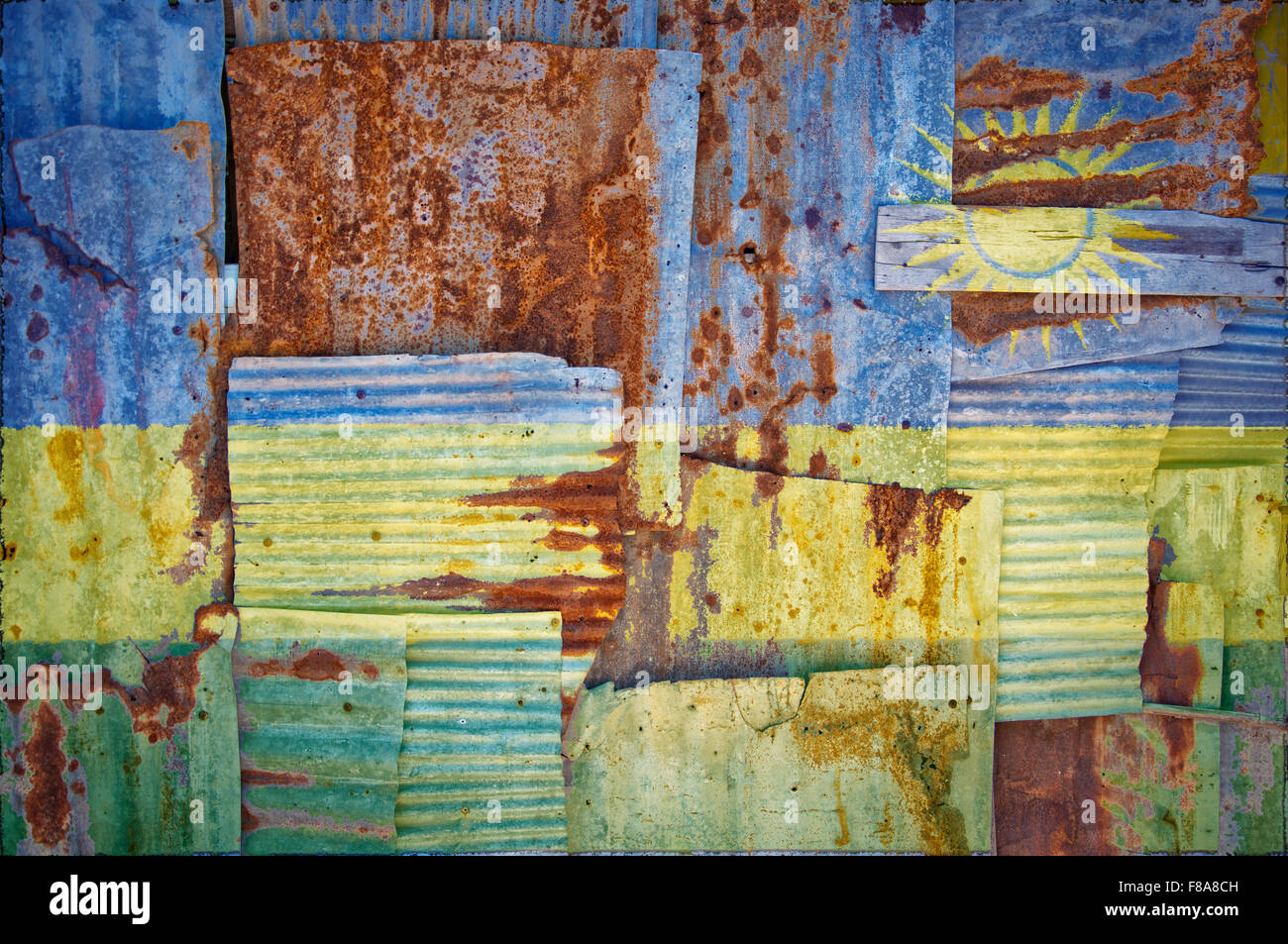 An abstract background image of the flag of Rwanda painted on to rusty corrugated iron sheets overlapping to form a wall Stock Photo