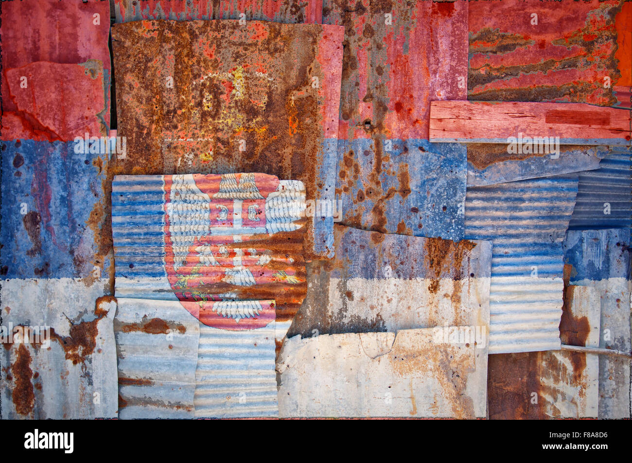 An abstract background image of the flag of Serbia painted on to rusty corrugated iron sheets overlapping to form a wall Stock Photo