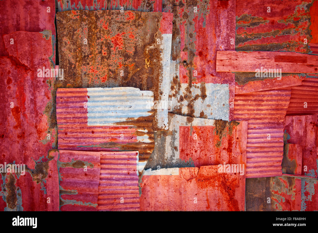 An abstract background image of the flag of Switzerland painted on to rusty corrugated iron sheets overlapping to form a wall Stock Photo