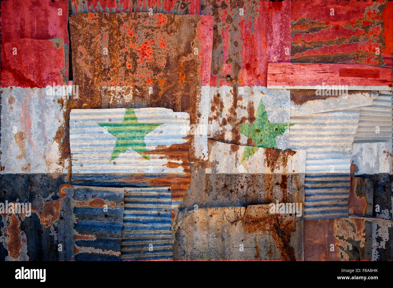 An abstract background image of the flag of Syria painted on to rusty corrugated iron sheets overlapping to form a wall or fence Stock Photo
