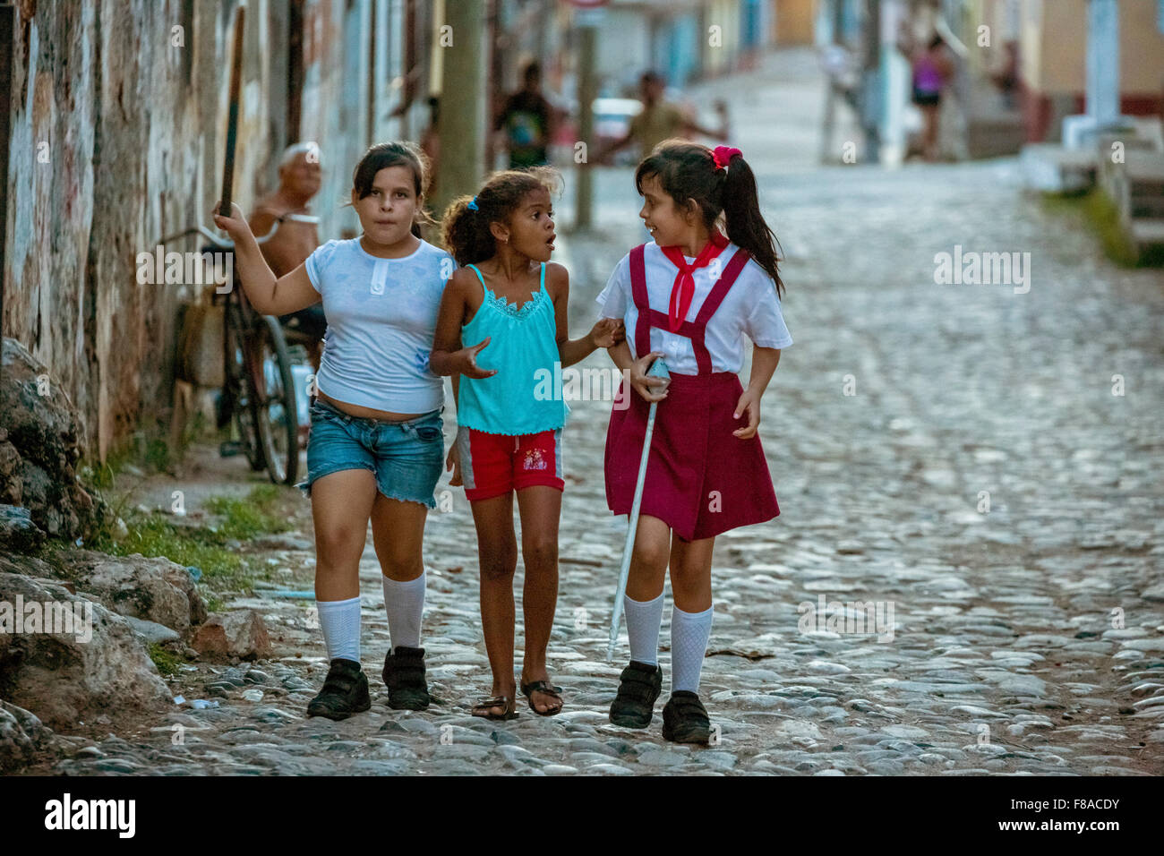 Three girls discuss on the road, school girls, children, Street scene in the old town of Trinidad, Trinidad, Cuba, Sancti Spírit Stock Photo