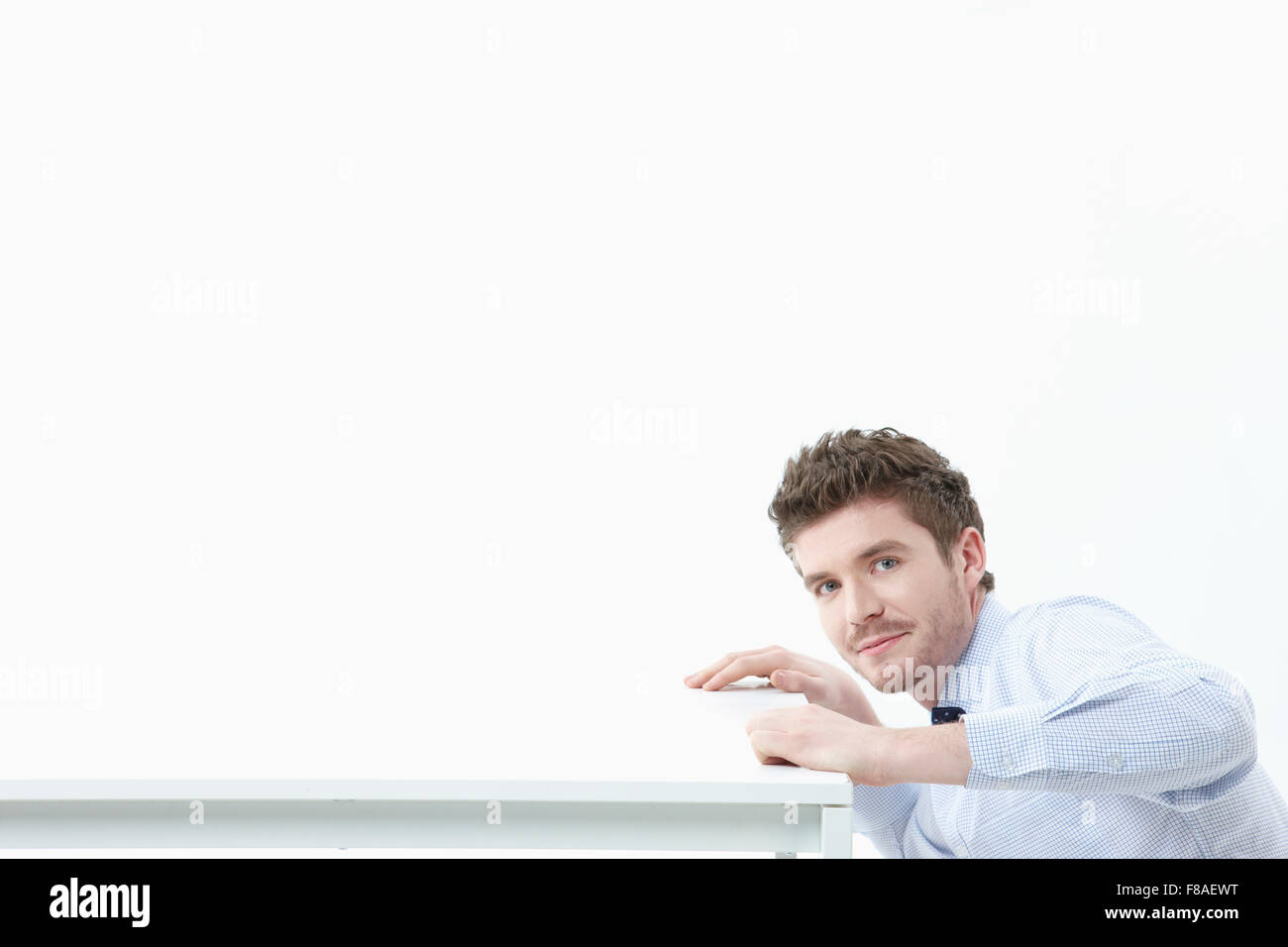 Smiling man sitting below at the right side of the desk Stock Photo