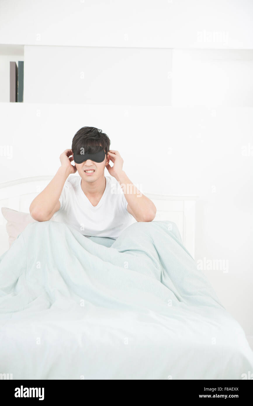 Stressed man wearing eye patch in bed Stock Photo