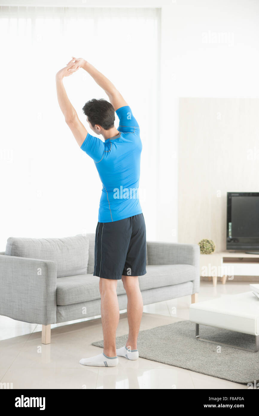 The back side of a man stretching his body in the living room Stock Photo